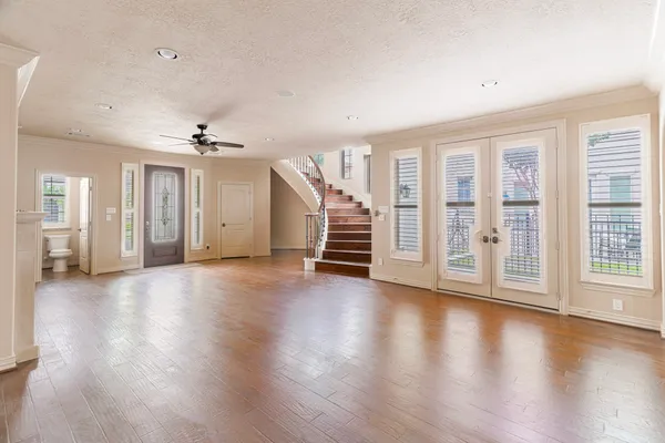 a view of an empty room with wooden floor and stairs