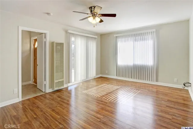 a view of empty room with wooden floor and fan