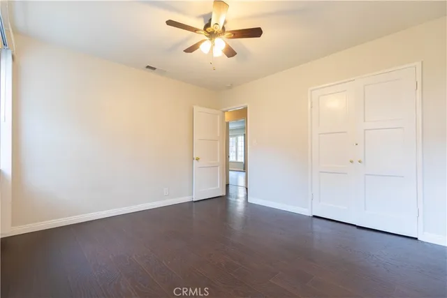 an empty room with wooden floor and fan