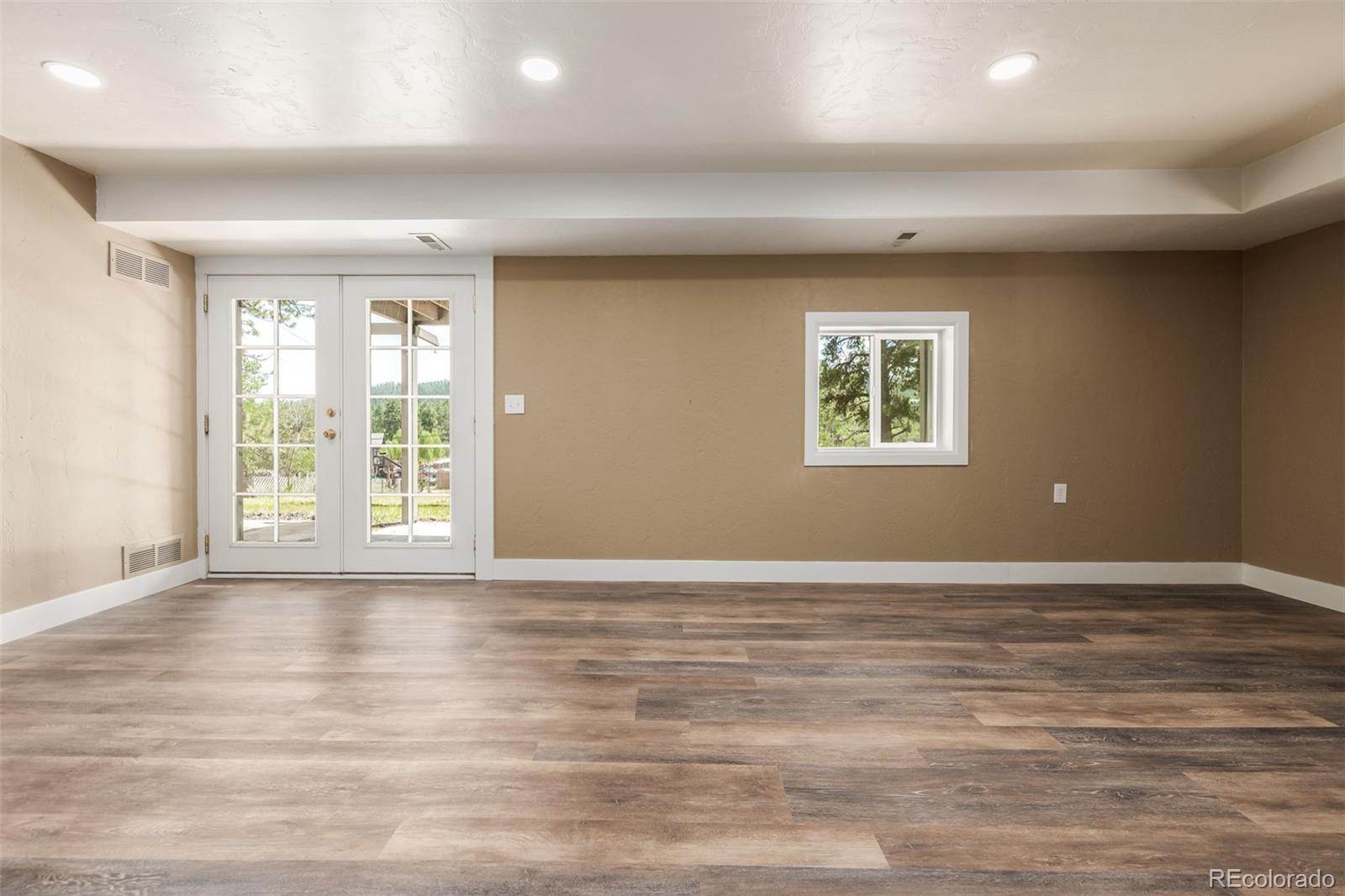 363 Neal Road Bailey, CO 80421 - Photo 16 of 39 an empty room with wooden floor and windows