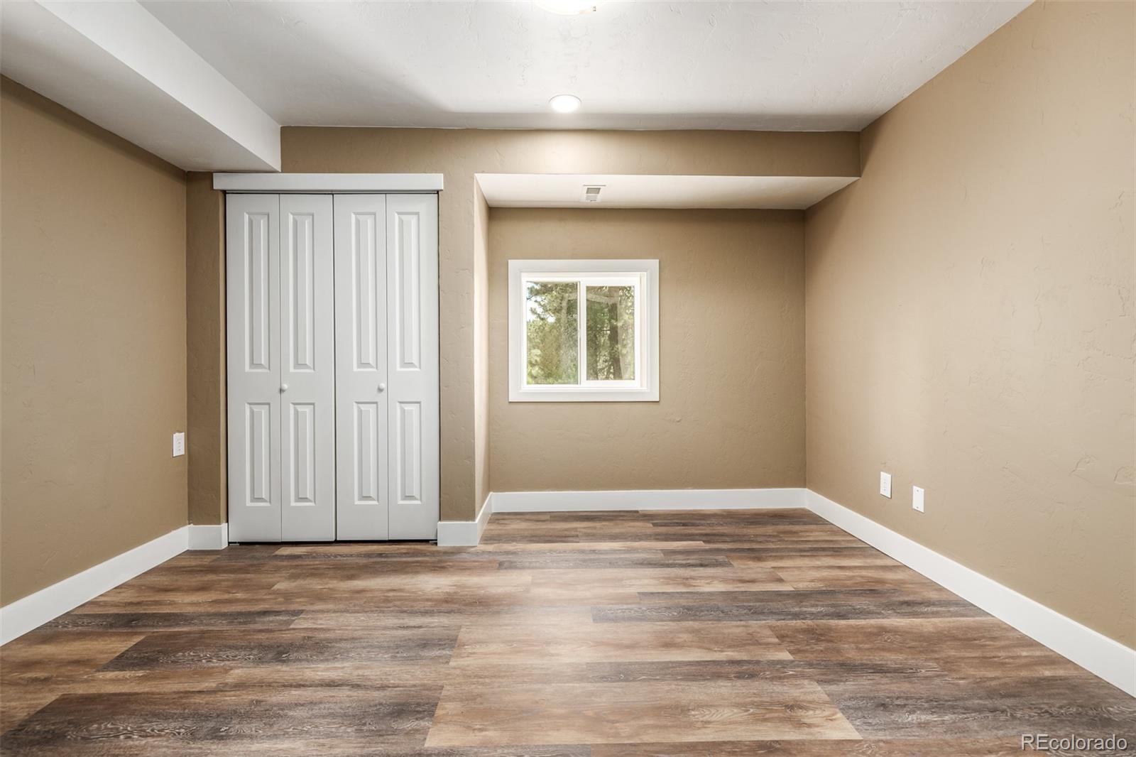 363 Neal Road Bailey, CO 80421 - Photo 18 of 39 a view of an empty room with wooden floor and a window