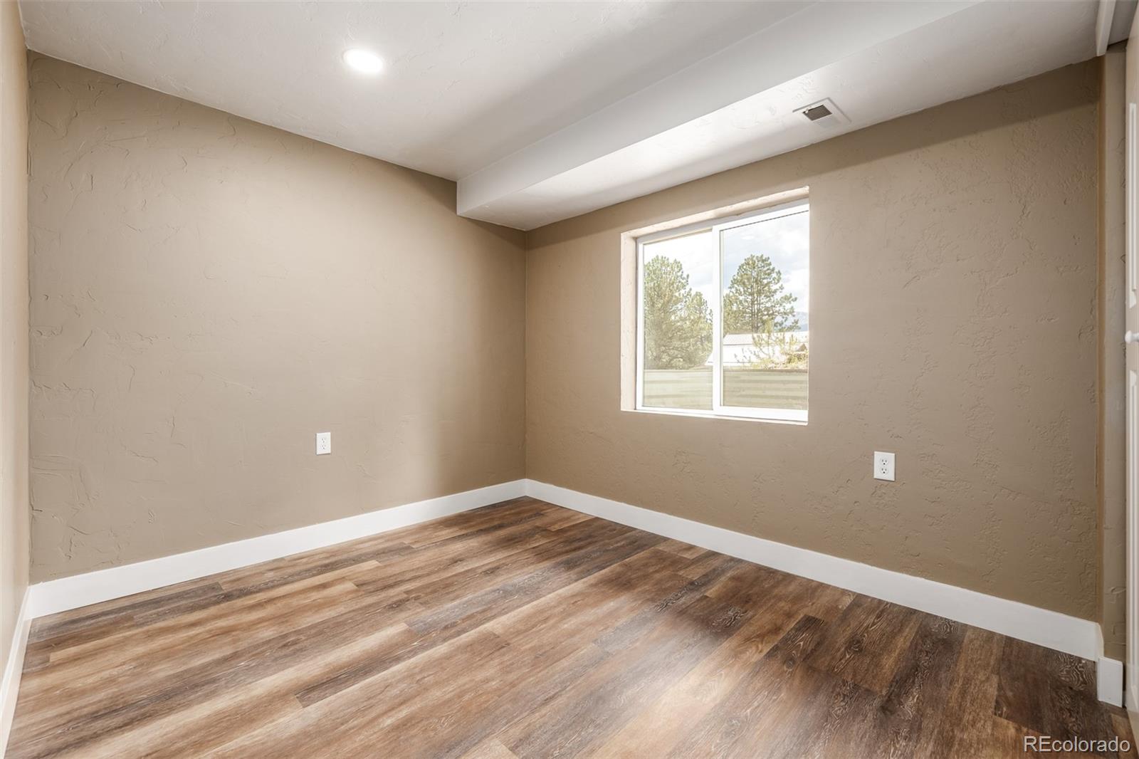 363 Neal Road Bailey, CO 80421 - Photo 19 of 39 a view of an empty room with wooden floor and a window