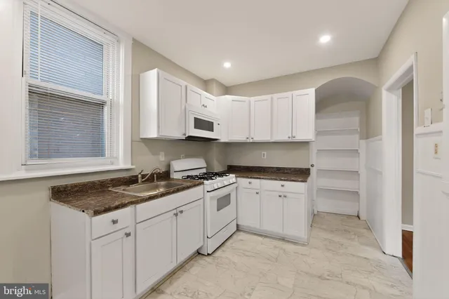 a kitchen with granite countertop a sink stove and cabinets