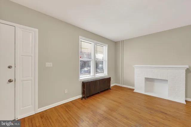 a view of empty room with wooden floor and fireplace