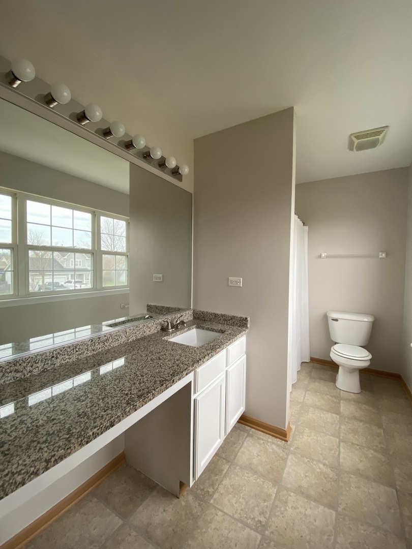 515 May Street Plano, IL 60545 - Photo 14 of 14 a spacious bathroom with a granite countertop sink and a mirror