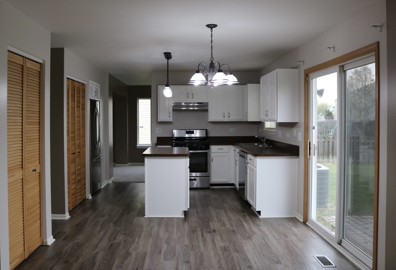 515 May Street Plano, IL 60545 - Photo 6 of 14 a kitchen with kitchen island granite countertop wooden floors stainless steel appliances a sink and a window