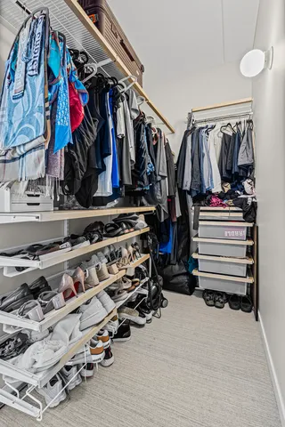 a view of walk in closet with clothes and shoes