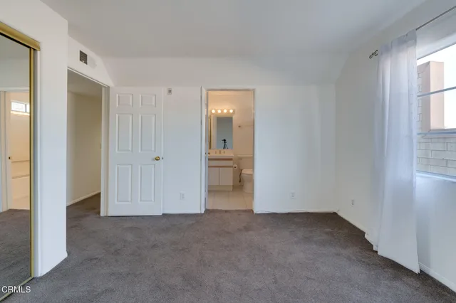 a view of an empty room with window and bathroom