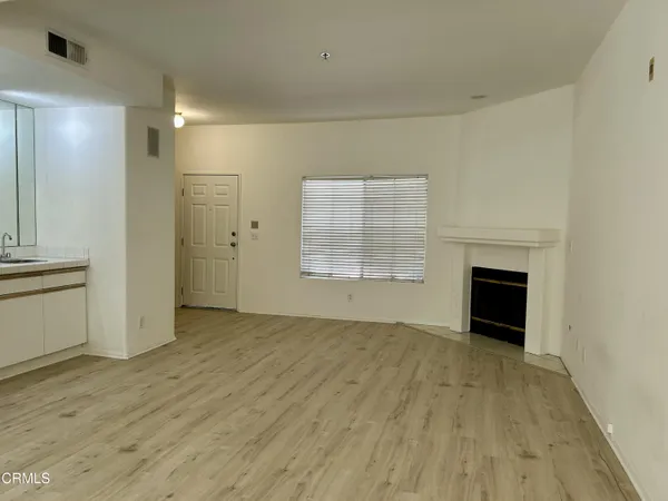 an empty room with wooden floor fireplace and windows