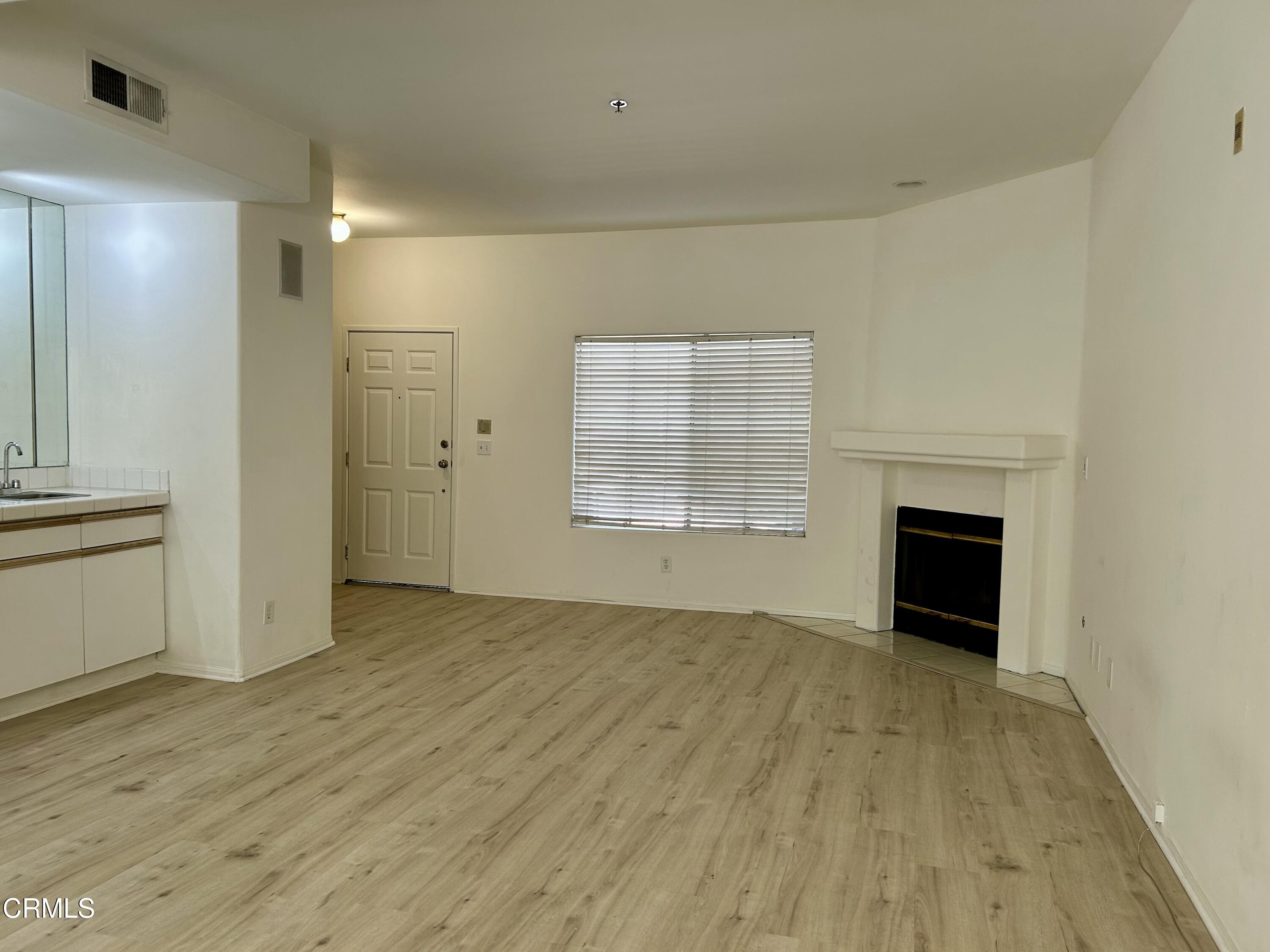 10925 Blix Street, Unit 102 Toluca Lake, CA 91602 - Photo 3 of 29 an empty room with wooden floor fireplace and windows