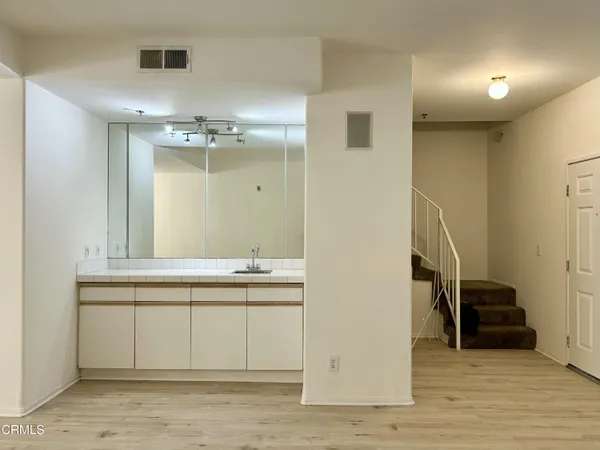a view of a hallway to a room with wooden floor and cabinet