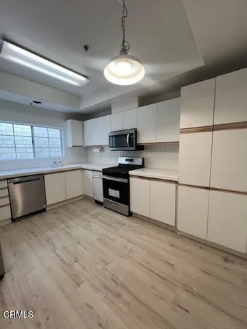 a kitchen with stainless steel appliances granite countertop a sink a stove a refrigerator and a microwave