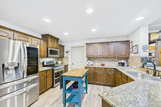a kitchen with a sink a counter top space a center island stainless steel appliances cabinets and a window