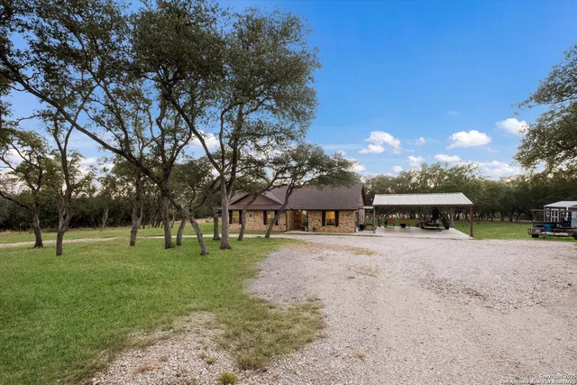 a view of a big yard with a house and trees in the background