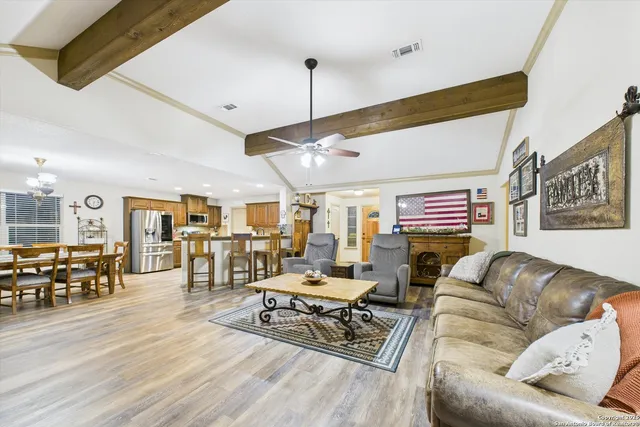 a living room with furniture kitchen view and a wooden floor