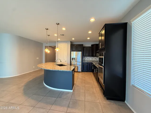 a view of kitchen with stainless steel appliances kitchen island granite countertop a refrigerator and a sink