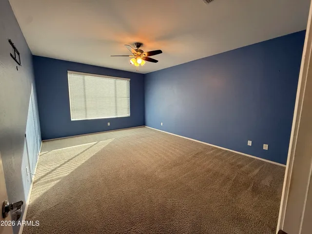 an empty room with windows and chandelier fan