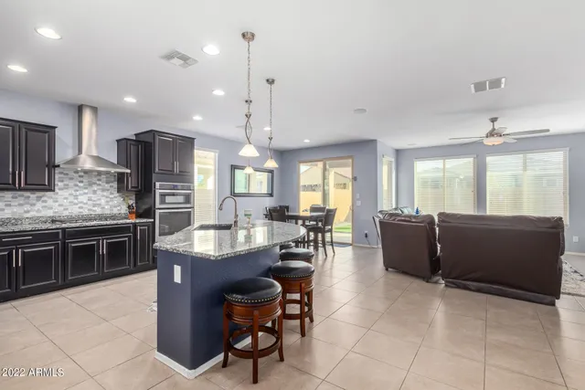 a large kitchen with kitchen island stainless steel appliances a stove a sink a oven a dining table and chairs