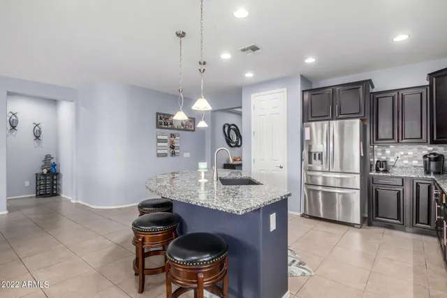 a kitchen with kitchen island granite countertop a stove a refrigerator and a sink