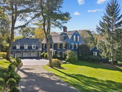 a front view of a house with a yard and large trees