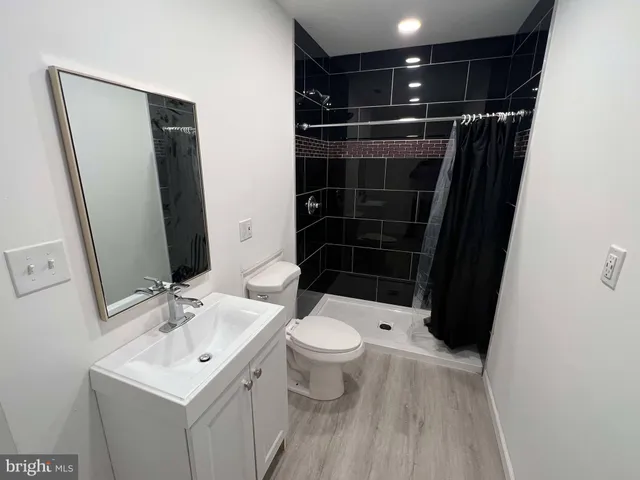 a bathroom with a sink a toilet a mirror and shower