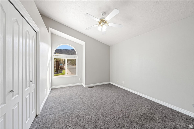 7 Reflection Way St. George, UT 84770 - Photo 36 of 54 Unfurnished bedroom featuring a closet, carpet, lofted ceiling, a textured ceiling, and a ceiling fan