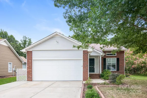 a view of a white house next to a yard and large trees