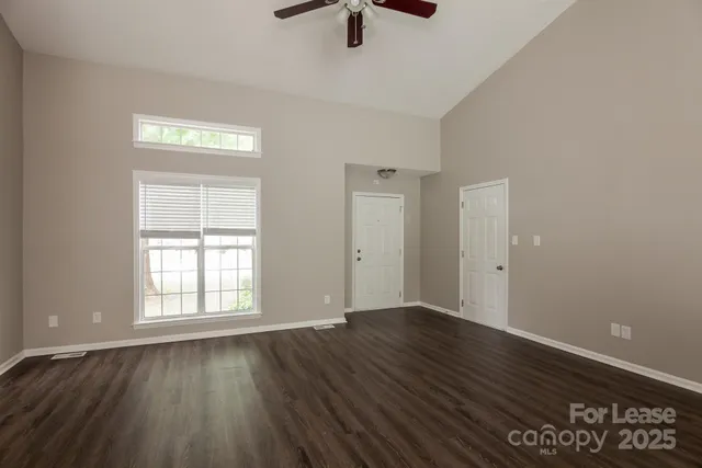 an empty room with wooden floor cabinet and windows
