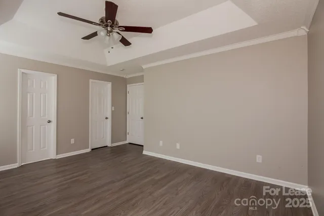 an empty room with wooden floor fan and windows