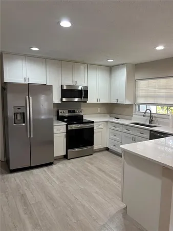 a kitchen with stainless steel appliances granite countertop white cabinets a refrigerator a sink a stove a microwave and island