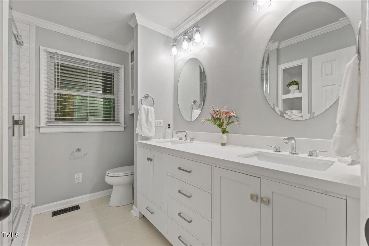 6713 Laurdane Road Raleigh, NC 27613 - Photo 18 of 47 a bathroom with a double vanity sink a toilet and a mirror
