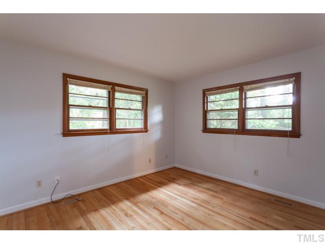 11709 Strickland Road Raleigh, NC 27613 - Photo 14 of 25 an empty room with wooden floor and windows