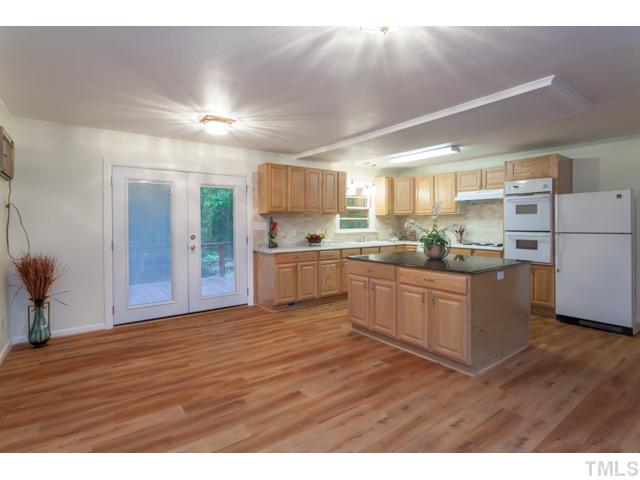 11709 Strickland Road Raleigh, NC 27613 - Photo 5 of 25 a kitchen with stainless steel appliances granite countertop a refrigerator a sink dishwasher a stove and white countertops with wooden floor