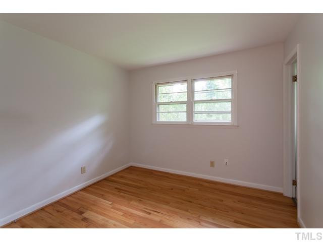 11709 Strickland Road Raleigh, NC 27613 - Photo 9 of 25 an empty room with wooden floor and windows