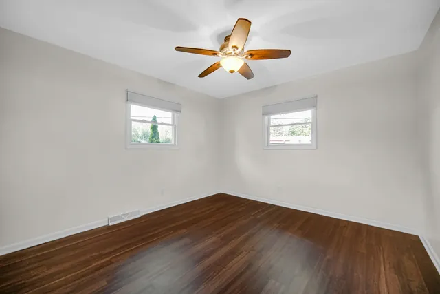 a view of wooden floor and a chandelier fan in a room