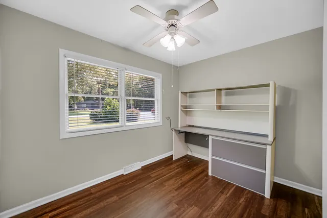 a view of an empty room with a window and wooden floor