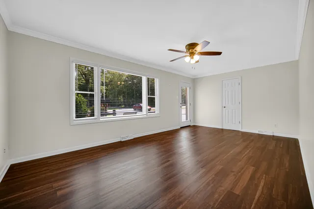 a view of an empty room with window and wooden floor
