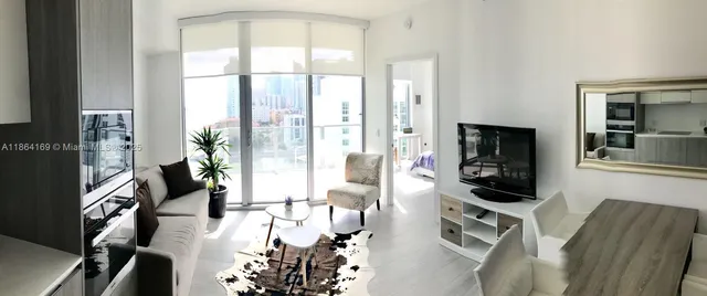 a living room with furniture a flat screen tv and floor to ceiling window