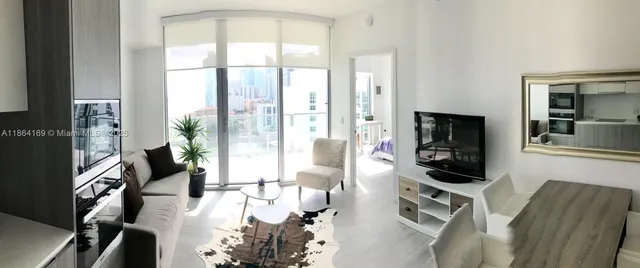 a living room with furniture a flat screen tv and floor to ceiling window