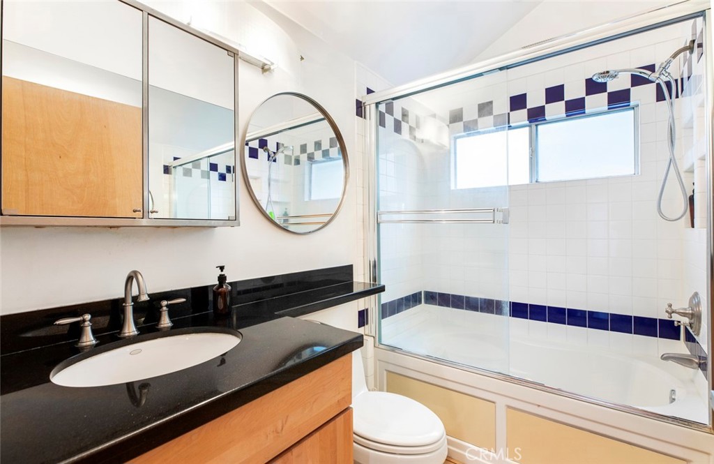 1447 Calumet Avenue, Unit B Los Angeles, CA 90026 - Photo 9 of 12 a bathroom with a granite countertop sink a mirror a bathtub and a shower