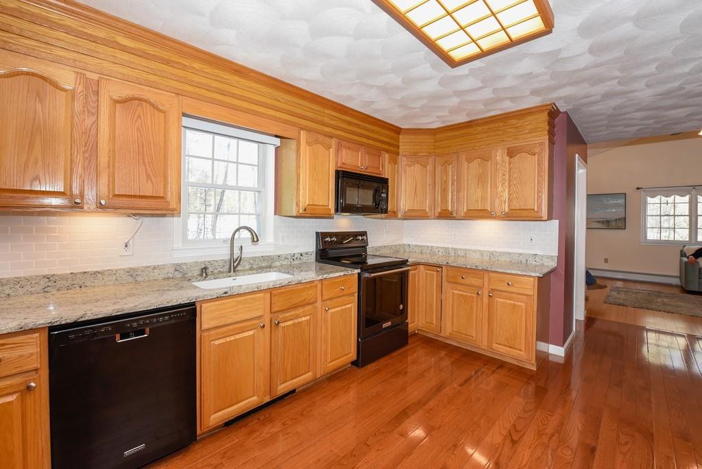 624 Boston Road Groton, MA 01450 - Photo 4 of 25 a kitchen with granite countertop a stove top oven a sink dishwasher and a microwave oven with cabinets