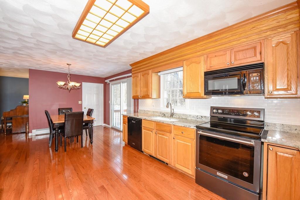 624 Boston Road Groton, MA 01450 - Photo 5 of 25 a kitchen with stainless steel appliances granite countertop a stove top oven a sink dishwasher a dining table and chairs with wooden floor
