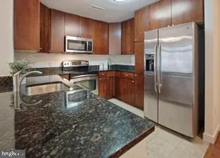 a kitchen with granite countertop a stove microwave and refrigerator