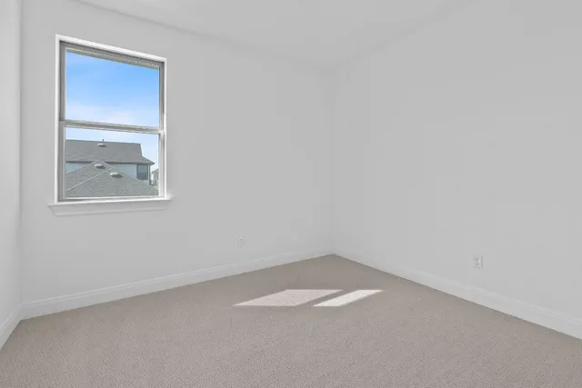 a view of an empty room with window and ceiling fan
