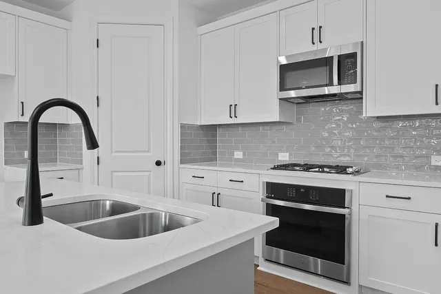 a kitchen with stainless steel appliances granite countertop a sink stove and microwave