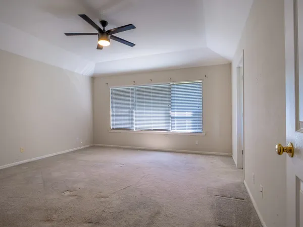 an empty room with windows and ceiling fan