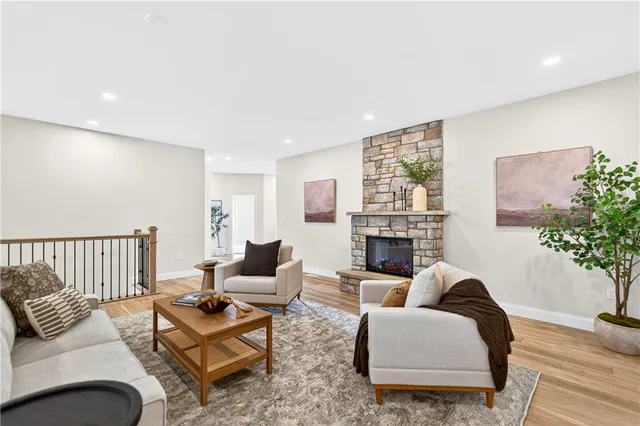 a living room with furniture a fireplace and potted plants with wooden floor