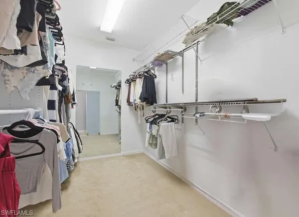 a view of walk in closet with clothes and shoes