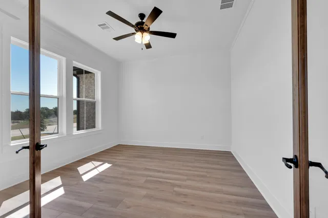 a view of empty room with wooden floor and fan