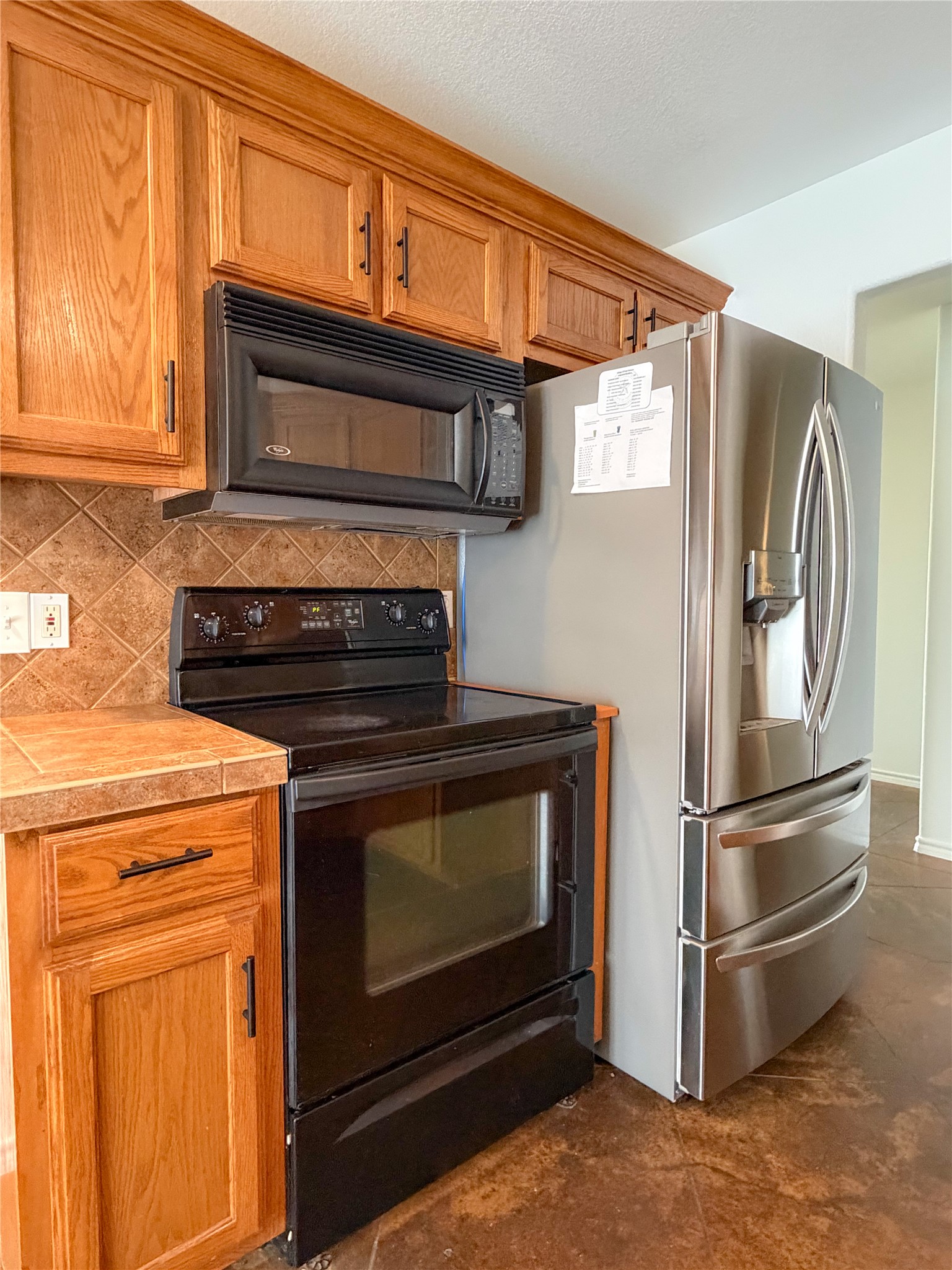 430 Summit Ridge Drive North Point Venture, TX 78645 - Photo 14 of 39 Kitchen with black appliances, wood finish cabinetry, and backsplash